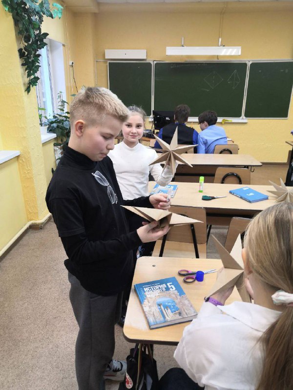 ⭐️Прилетаем в Россию!⭐️В нашей стране постепенно возрождается традиция оформлять рождественские елки в истинно русском стиле, превращая их в яркое отражение национальной культуры и семейных ценностей. Это не просто стремление придерживаться строгих канонов, а глубокая дань уважения нашим корням, атмосфере домашнего уюта и культурной преемственности поколений.Ребята 5 класса создали своими руками оригинальные праздничные украшения для своего кабинета, выдержанные в традиционном русском стиле. Ёлочку украсили гирляндами из сушек связанных яркими красно-зелёными лентами, бумажными  звёздами. Дверь украсили старинным символом Нового года - рождественским венком. Дополнительно повесили искусственные ветви ели, яркие бусы, нарядные шарики и изящные бумажные гирлянды-флажки. Мягко мерцающие электрические гирлянды завершают картину традиционной красоты.Декор в стиле «а-ля рус» (русский стиль) - это оформление интерьера, сочетающее элементы традиционного русского стиля с актуальными модными тенденциями. Такой декор может включать использование определённых цветов, материалов и орнаментов. Для русского стиля характерны естественные оттенки - синий, белый, зелёный, болотный, коричневый, чёрный, золотой.В декоре в стиле «а-ля рус» часто используют натуральные материалы. Некоторые из них: дерево - сосна, дуб, лиственница и берёза. Текстиль - лён, хлопок и шерсть - используют ковры, покрывала, подушки и шторы. Камень и глина - печи, изразцовые элементы, декоративные панели. Керамика и глазурованная посуда - выступают в роли современных декоративных деталей, которые отсылают к другим эпохам.Также в декоре могут использоваться растительные и звериные орнаменты: деревья, ветки, ягоды, лошади и петухи.Декор ёлки в русском стиле - это не просто украшение праздника, это способ передать тепло дома, традиции и культурное наследие. Дом, где чтят старину, а вместе с тем живут настоящими праздниками.